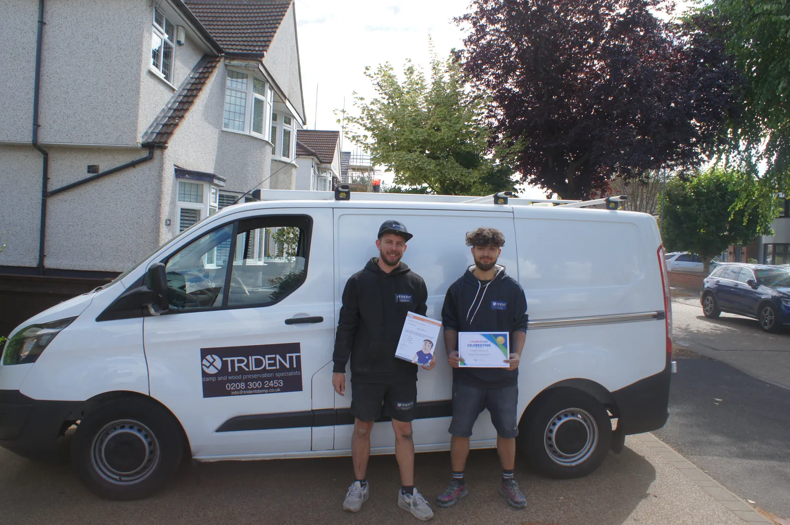 Two Trident Damp team members standing by the company van