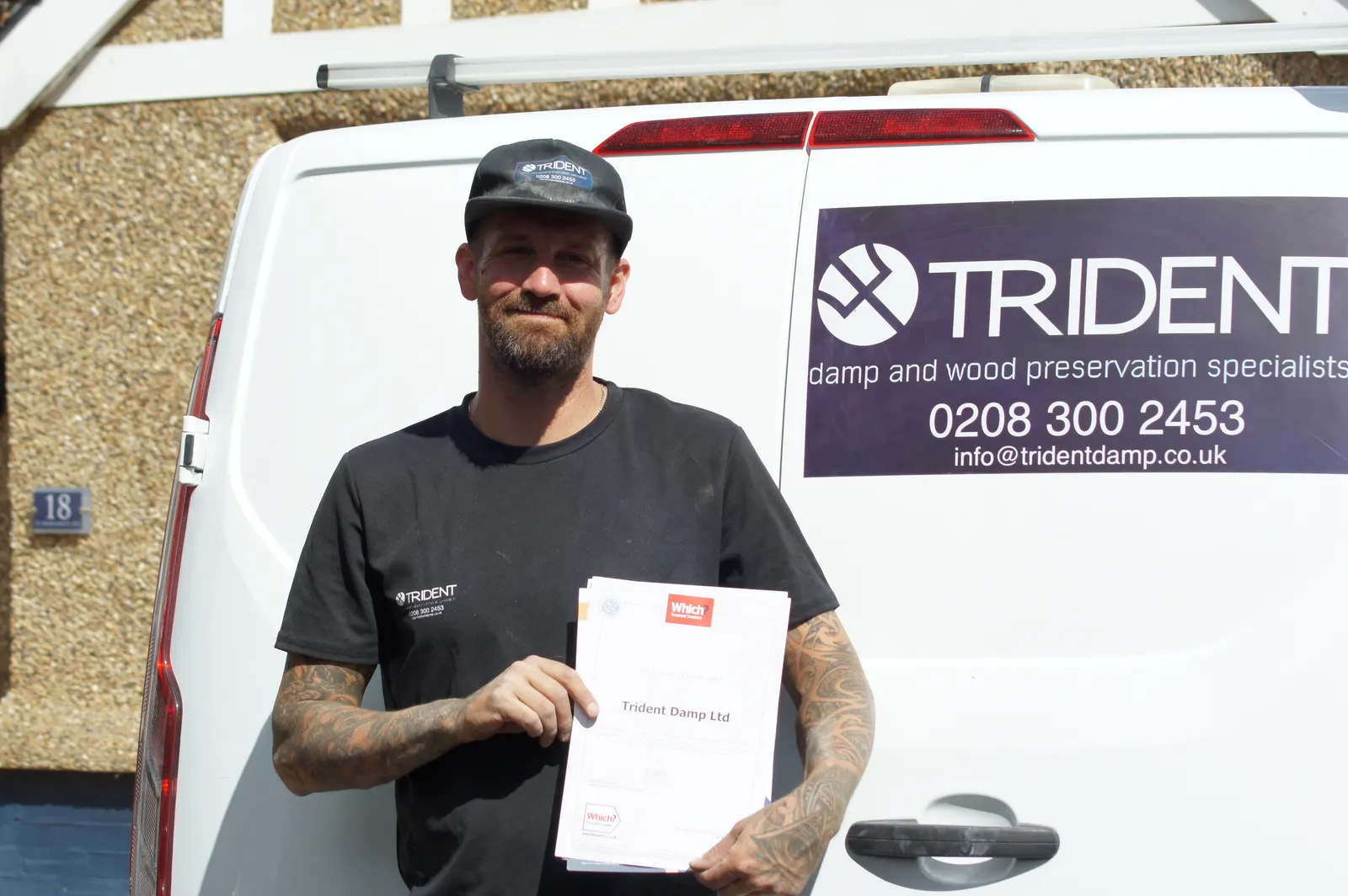 Robert of Trident Damp in company workwear holding the Which? Trusted Traders certificate by the van